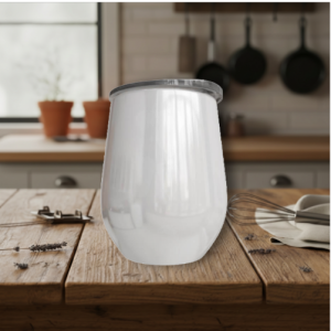 Glass milk carafe on a wooden kitchen table, with a whisk and plates in the background.
